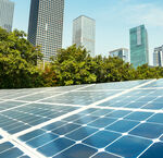 Solar panels arrayed in front of a city skyline with skyscrapers and trees